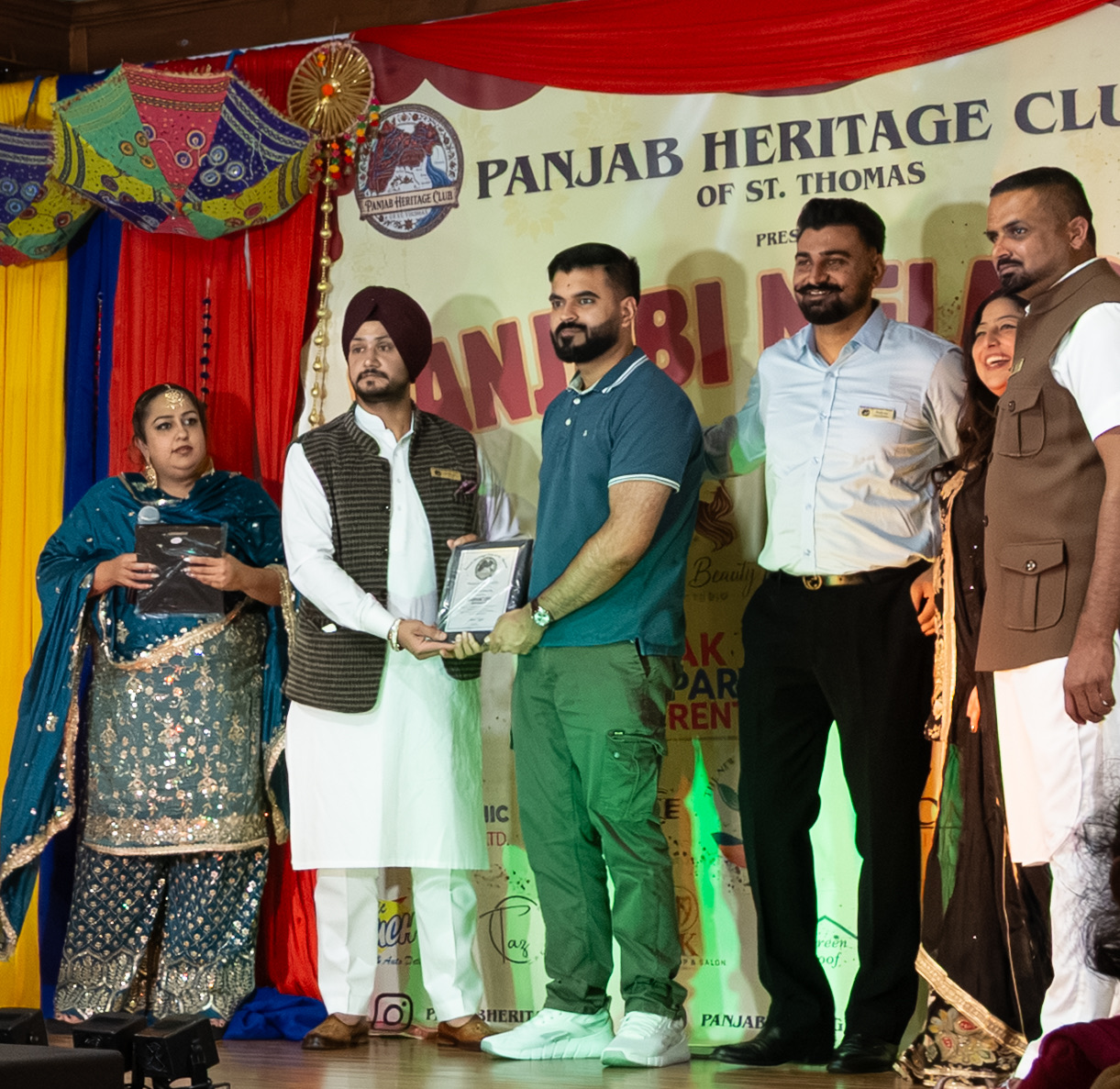 Hasham receiving a photography award plaque on stage at Panjabi Mela 2026, Panjab Heritage Club of St. Thomas